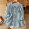 Light blue embroidered linen shirt with frog buttons on a hanger