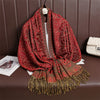 Red paisley patterned shawl with tassels draped over a chair