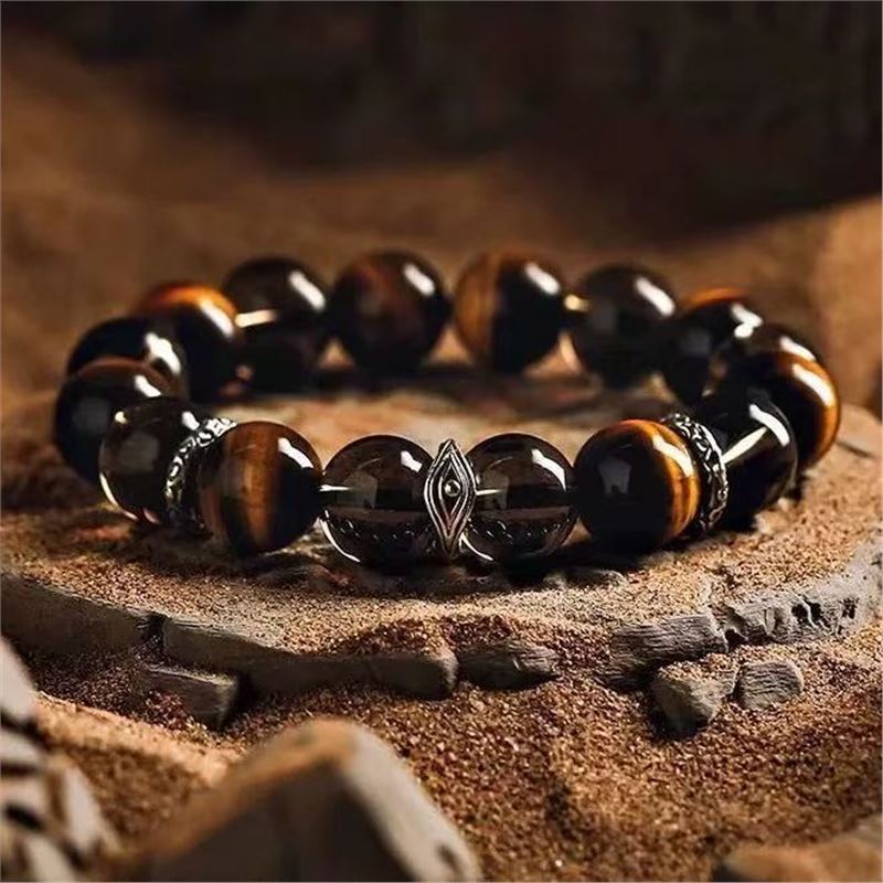 Close up of a brown bead bracelet with a silver tone metal charm on a wooden surface