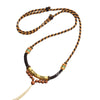 Close up of a brown and gold hand-braided necklace with alloy beads and tassel ends.