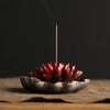 Close up of a red ceramic lotus flower incense burner held in hand