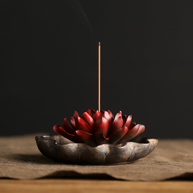 Close up of a red ceramic lotus flower incense burner held in hand