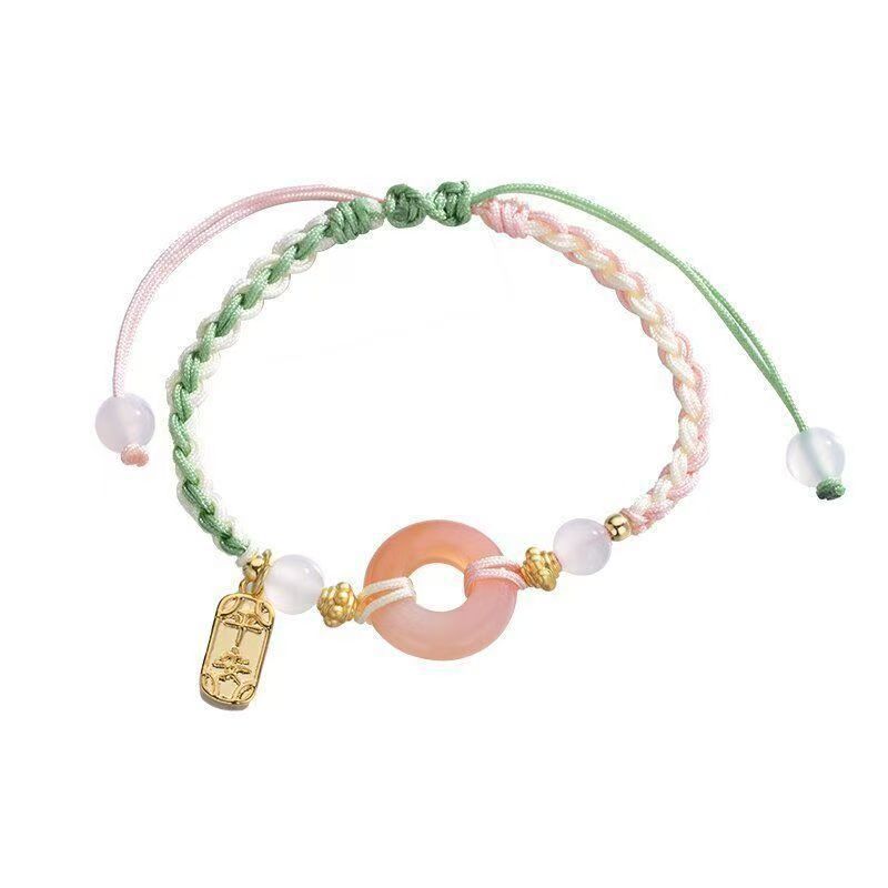 Pink and green braided cord bracelet with a central peace buckle ring and gold-tone Ruyi lock charm