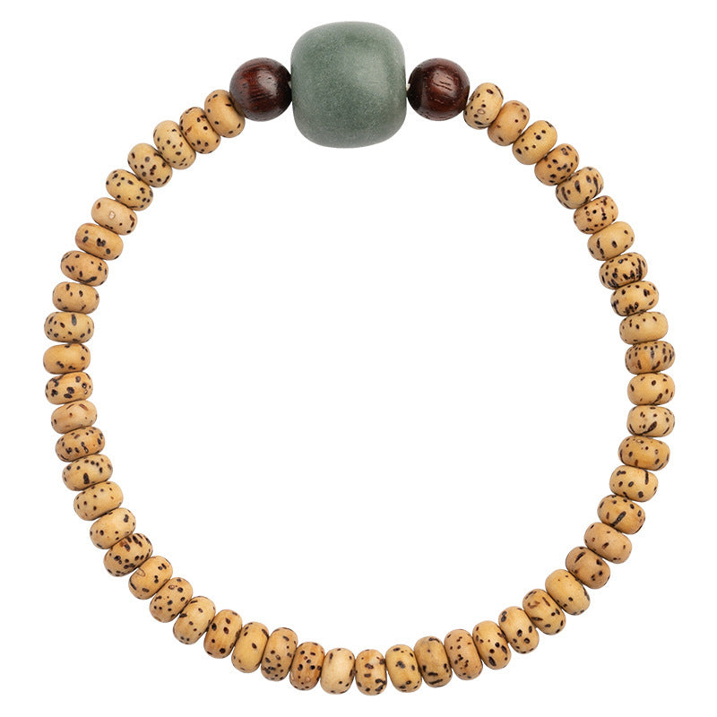 Close up of a Star and Moon Bodhi seed bracelet with a green accent bead on a wrist