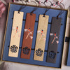 Four wooden bookmarks with painted oriole birds displayed in a blue gift box