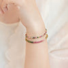 Wrist wearing a thin multicolor beaded tourmaline bracelet with gold clasp