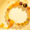 Close up of a yellow and brown multi-stone beaded bracelet with a guru bead