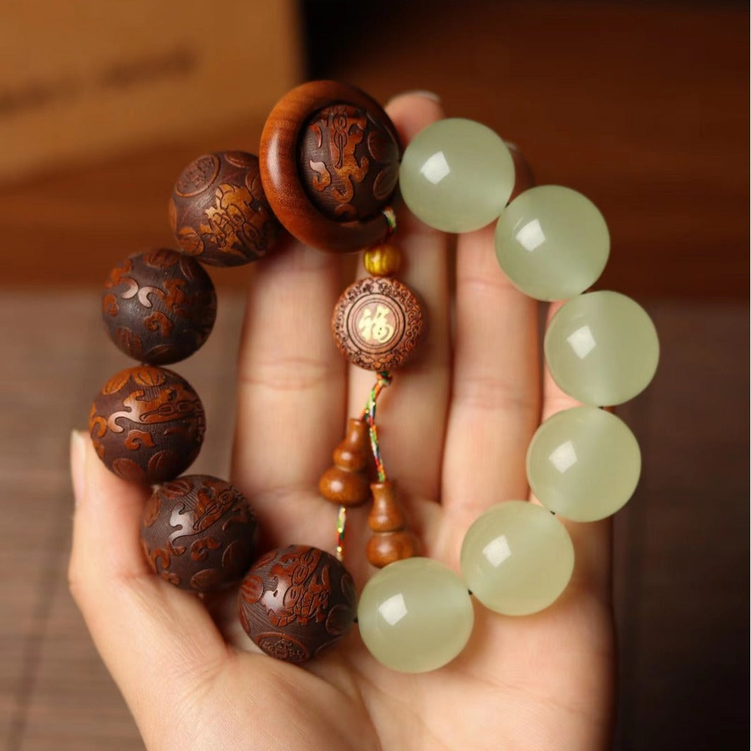 Hand holding a bracelet with half dark wood beads and half pale green jade beads
