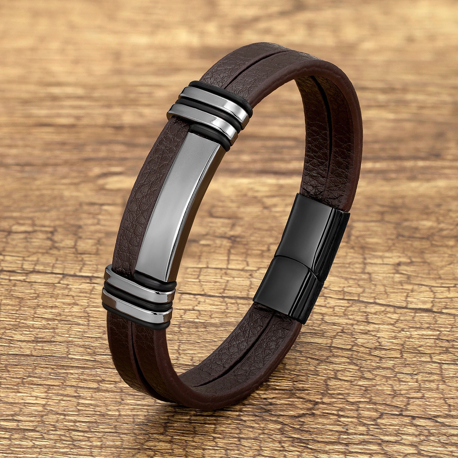 Brown leather bracelet with a silver-tone metal bar and black accents on a wood background