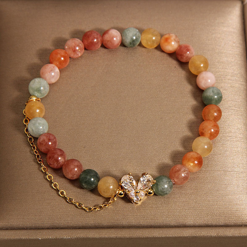 Close up of a multicolor crystal bracelet with a gold V-shaped charm on a box
