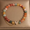 Close up of a multicolor crystal bracelet with a gold V-shaped charm on a box