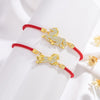 Close-up of a red string bracelet with a gold-tone horse charm paved with clear stones