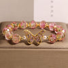 Pink glass bead bracelet with rose pattern and gold butterfly charm
