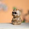 Close up of a small green sandalwood tiger carving wearing sunglasses on a wooden surface
