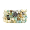 Multi-strand natural stone mala bracelet with a silver lotus charm on a white background