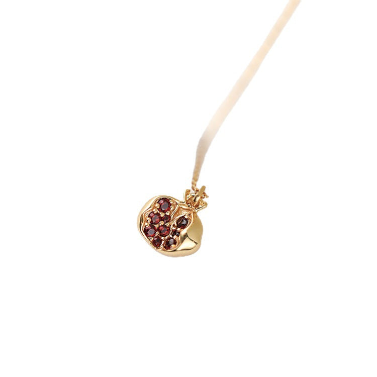 Close up of a gold plated sterling silver pomegranate pendant necklace with red stones