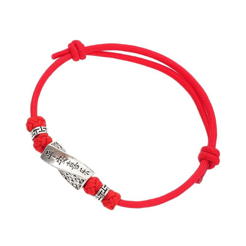 Red cord bracelet with a silver-tone cylinder charm engraved with mantras