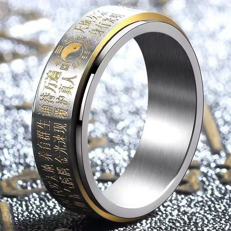 Close up view of a silver tone metal ring with gold trim and engraved text