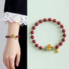 Red cinnabar beaded bracelet with gold horse charm and Fu tag on wrist