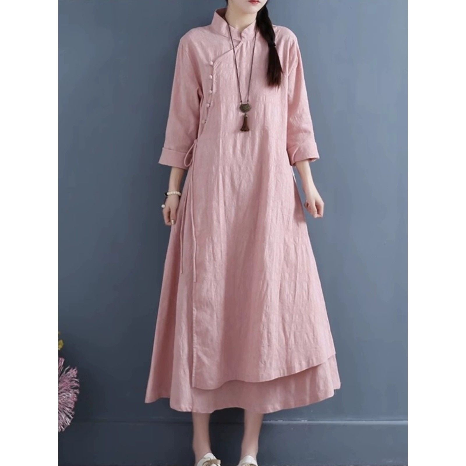 Woman wearing a pink long sleeve dress with frog buttons and a layered skirt