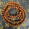 Close up of brown wooden prayer beads with engraved characters on a dark textured background