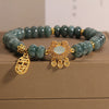 Close-up of a green jade bead bracelet with a gold-tone lock charm and abacus beads