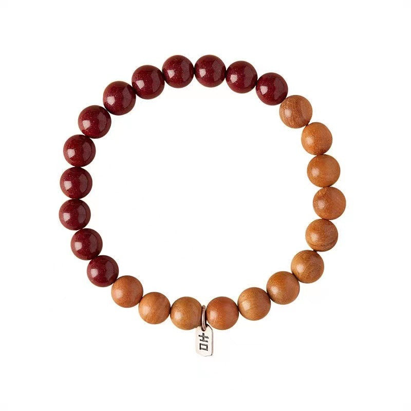 A circular bracelet made of red cinnabar and light brown peach wood beads on a white background