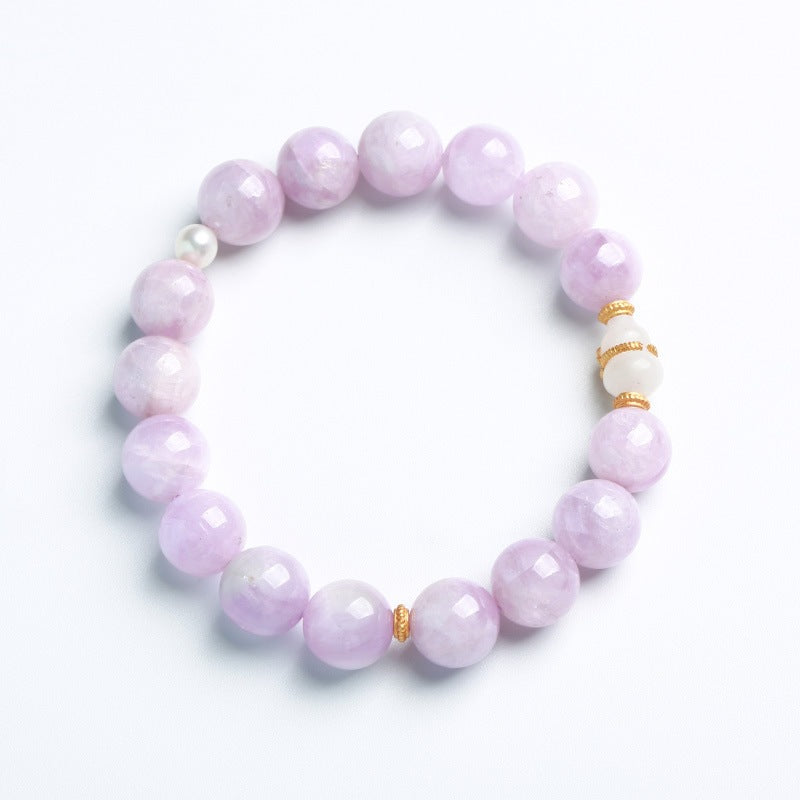 Lavender Kunzite beaded bracelet with white jade gourd charm on a book