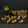 A collection of small ceramic Chinese zodiac animal figurines in yellow glaze arranged on a dark mat.