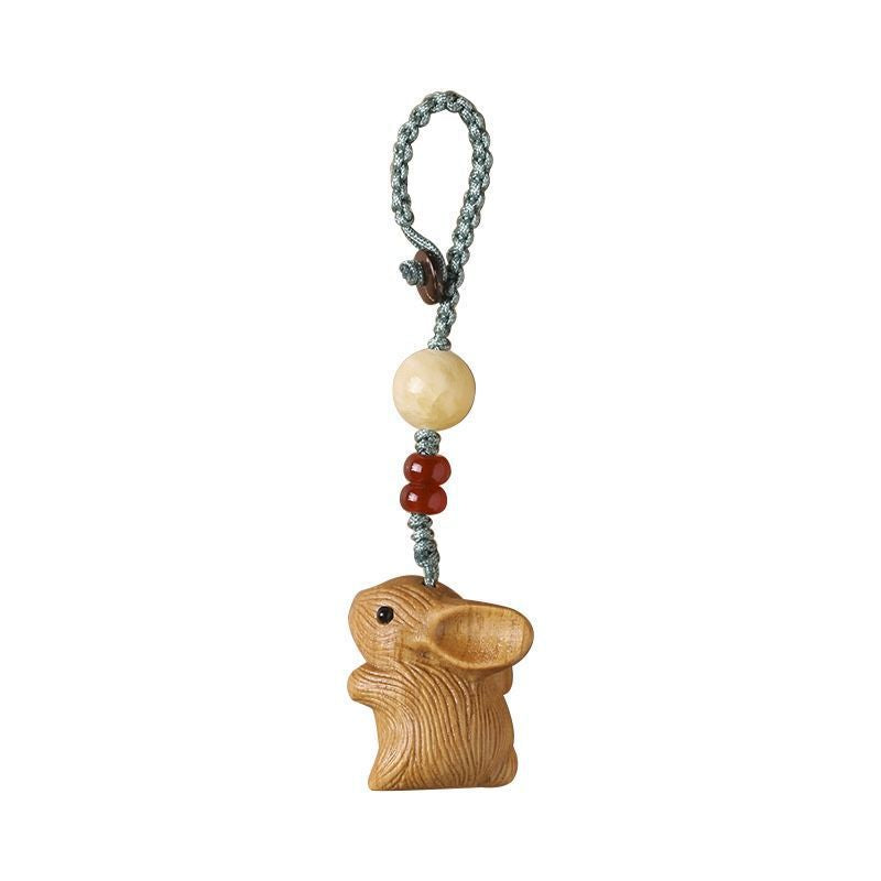 Carved white sandalwood rabbit hanging from a green cord loop with cream and dark beads.