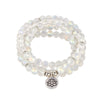 Close up of a white moonstone beaded necklace with a silver lotus pendant on a wooden surface