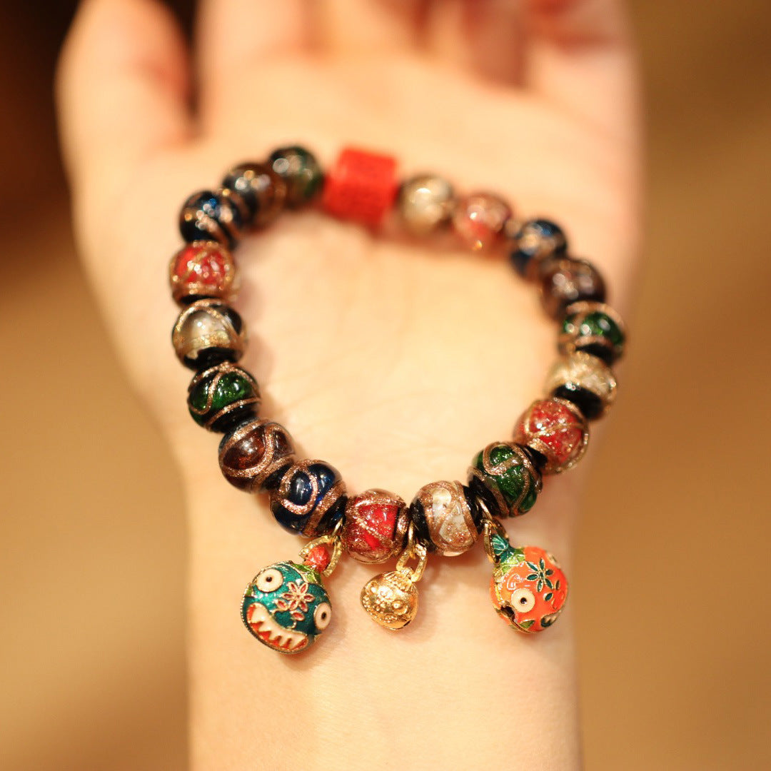 A wrist wearing a multi-colored glass bead bracelet with small hanging charms.