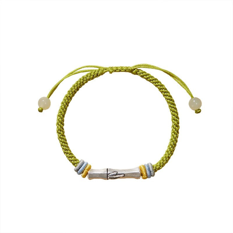 Close up of a woven bracelet with a silver bamboo charm on a wrist