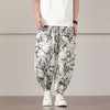 Man wearing loose white harem pants with black bamboo print and drawstring waist