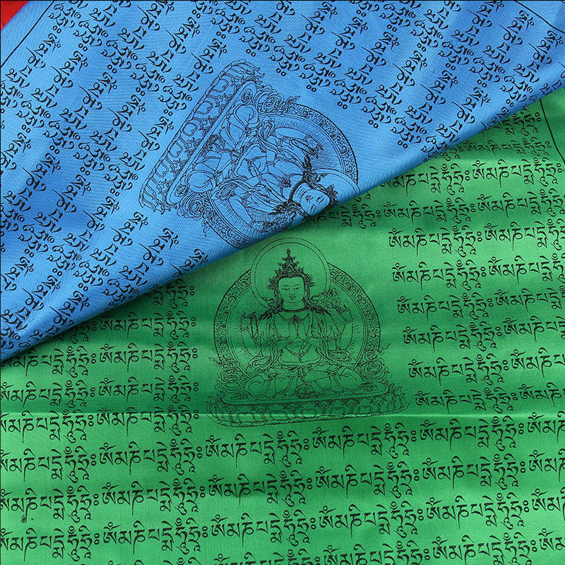 Close up view of blue and green Tibetan prayer flags with printed mantras and deity illustrations