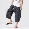 Man wearing dark blue loose linen pants with a white t-shirt and sandals