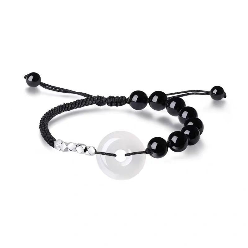 A close-up view of the black obsidian and white chalcedony peace buckle bracelet on a wrist.