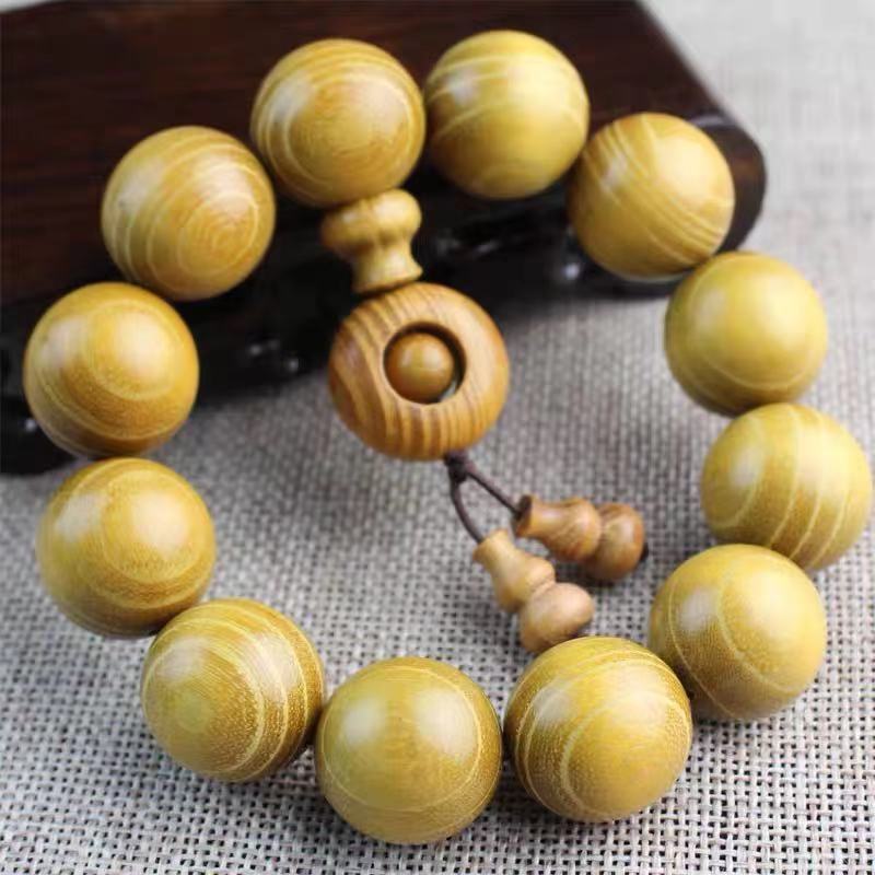 Close-up of a light-colored wooden bead bracelet with a guru bead and tassel.