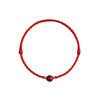 Close up of a red braided bracelet with a single cinnabar bead on a wrist