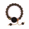 Dark wood bead bracelet with a black coin charm on a wrist