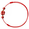 Close up of a red cord anklet with a red four-leaf flower charm on an ankle