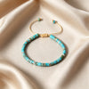 A turquoise natural stone bracelet with gold spacers on a beige silk background