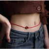 Red velvet waist chain with cinnabar peace buckle worn on bare skin above jeans