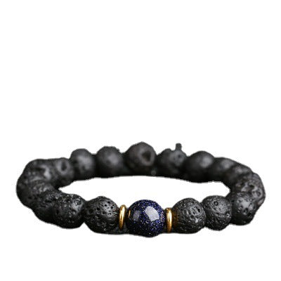 A stretchy bracelet made of black porous lava rock beads with one blue speckled bead in the center.