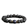 A stretchy bracelet made of black porous lava rock beads with one blue speckled bead in the center.