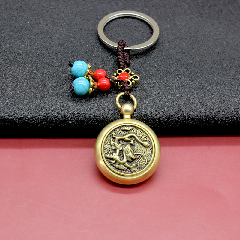 Close up of a brass keychain with a spinning horse medallion and blue beads