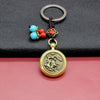 Close up of a brass keychain with a spinning horse medallion and blue beads