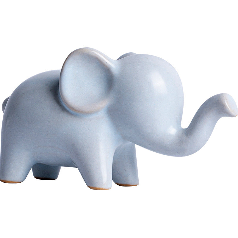 A small ceramic elephant figurine sitting on a wooden desk