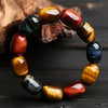 Close-up of a natural multi-color tiger eye bracelet with barrel-shaped beads on a wooden surface