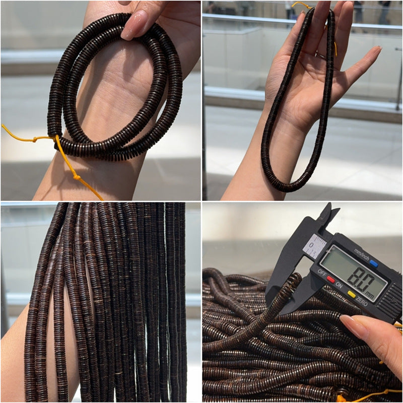 Strands of dark brown coconut shell beads held in hand